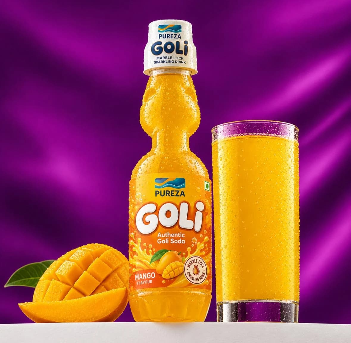 A marble-lock bottle of PUREZA Goli mango soda beside a filled glass and sliced mango